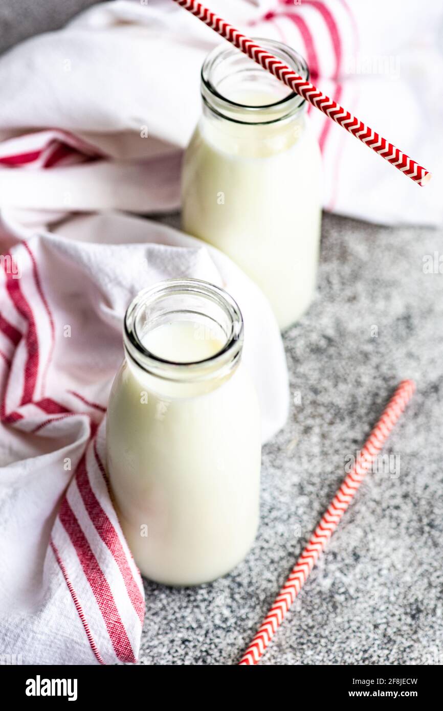 Two bottles of milk and drinking straws on table next to a tea towel Stock Photo