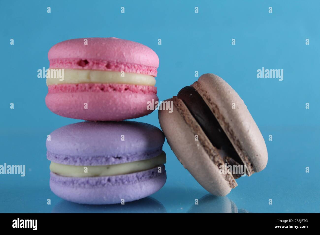three macaroons lie triangle on a blue background with a place for text and copyspace. Stock Photo