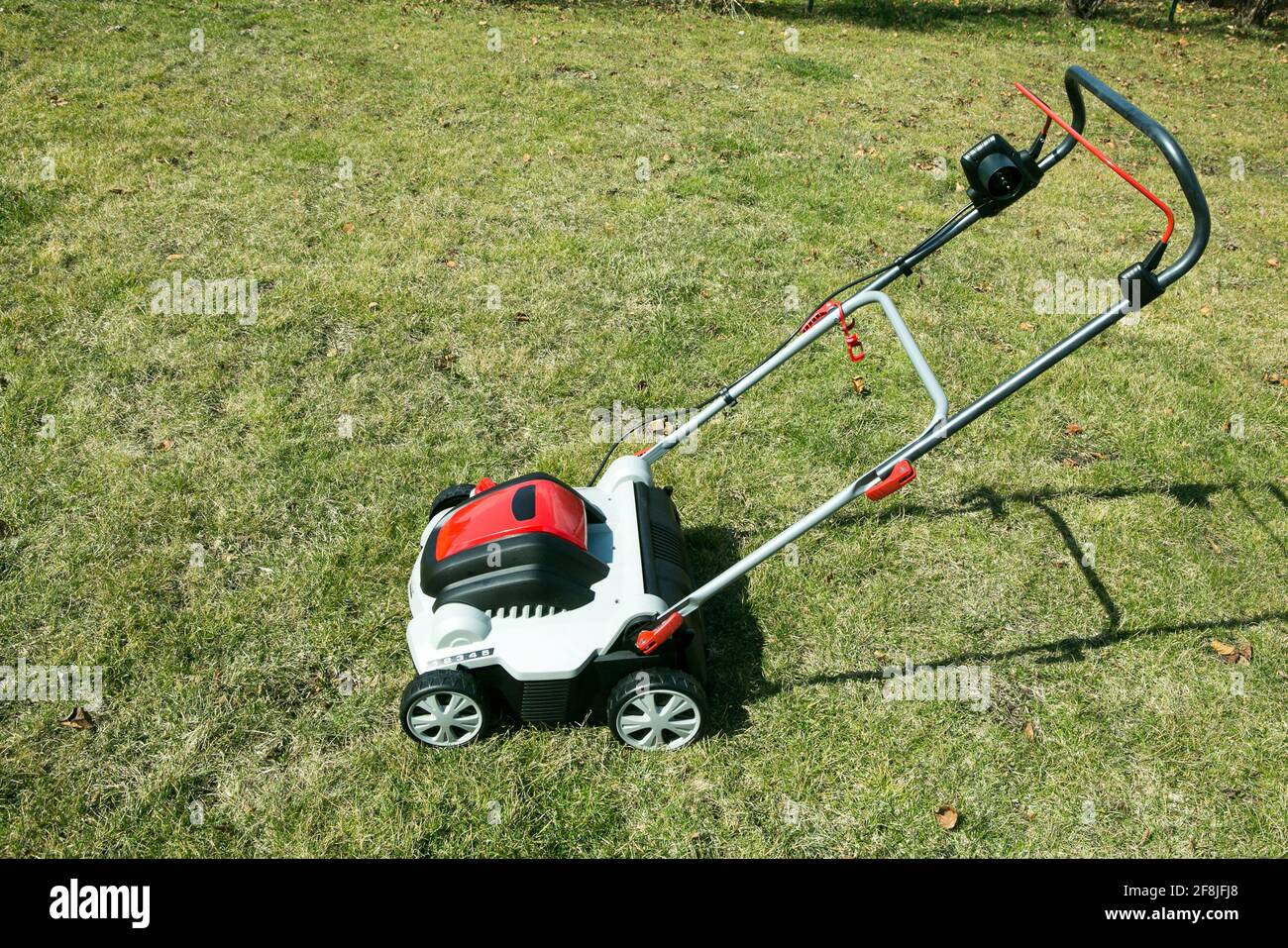 Aerator standing in grass. Aeration with a scarifier. Using a scarifier in the garden to improving quality of the lawn in spring. Stock Photo