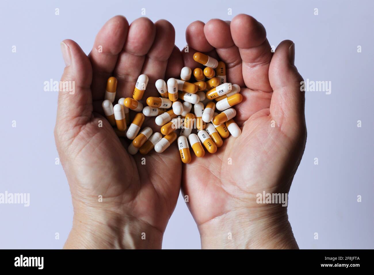 Hand with pills of omeprazole medication for treatment of GERD peptic ulcer & Zollinger Ellison syndrome. Used to treat stomach and esophagus problems Stock Photo