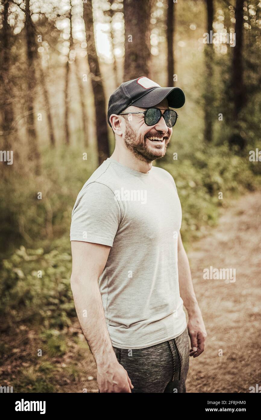 Man with cap and sunglasses smiling in a beautiful forest Stock Photo ...