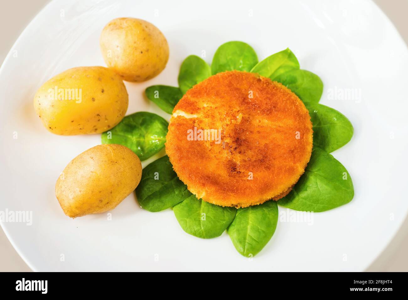 Cheese fried in breadcrumbs on salad leaf bed with boiled potato. Typicaly and traditionaly Czech food, available in most restaurants in Czech republi Stock Photo