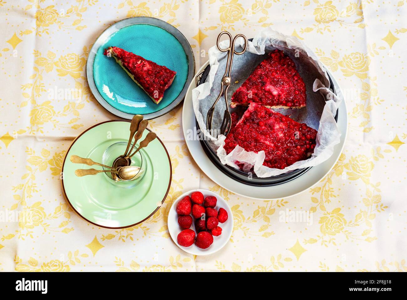 Overhead view on table with plate and cake form with red fruit cakes, empty dirty plate with spoons, strawberries on small plate. Stock Photo
