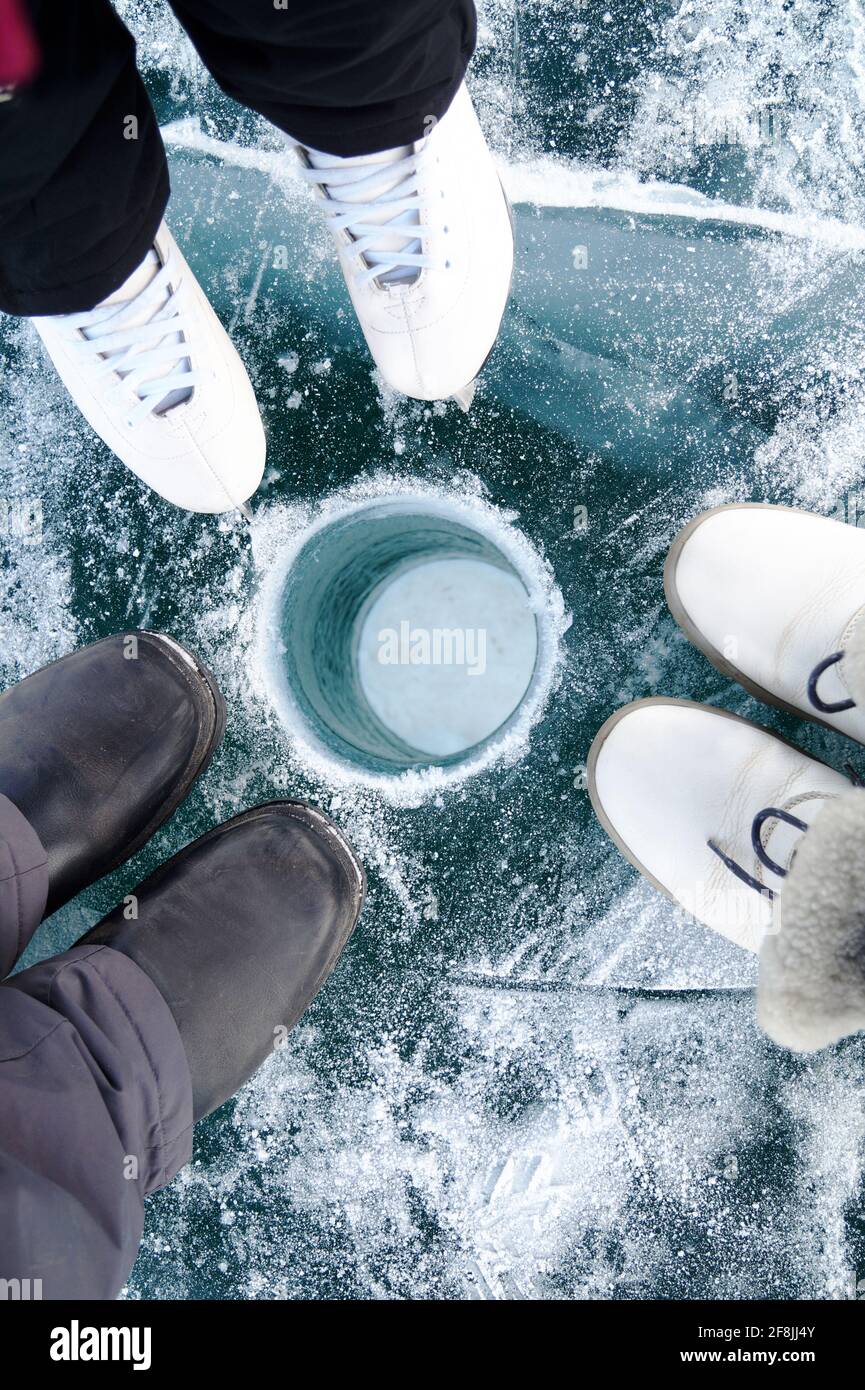 Top view of the ice fishing hole, shoes and skates Stock Photo