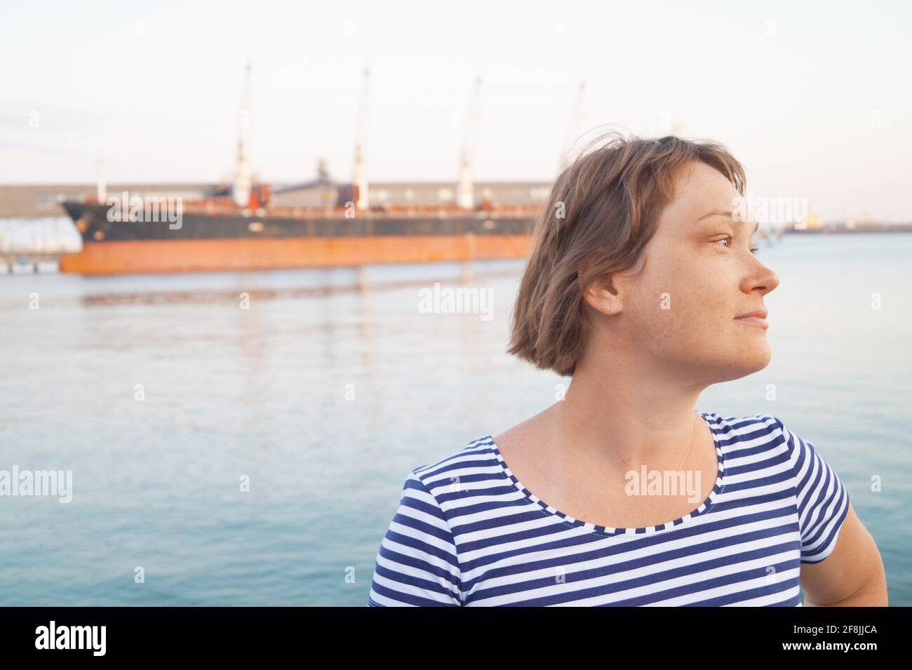 A woman looks to the side against the background of the ship Stock Photo