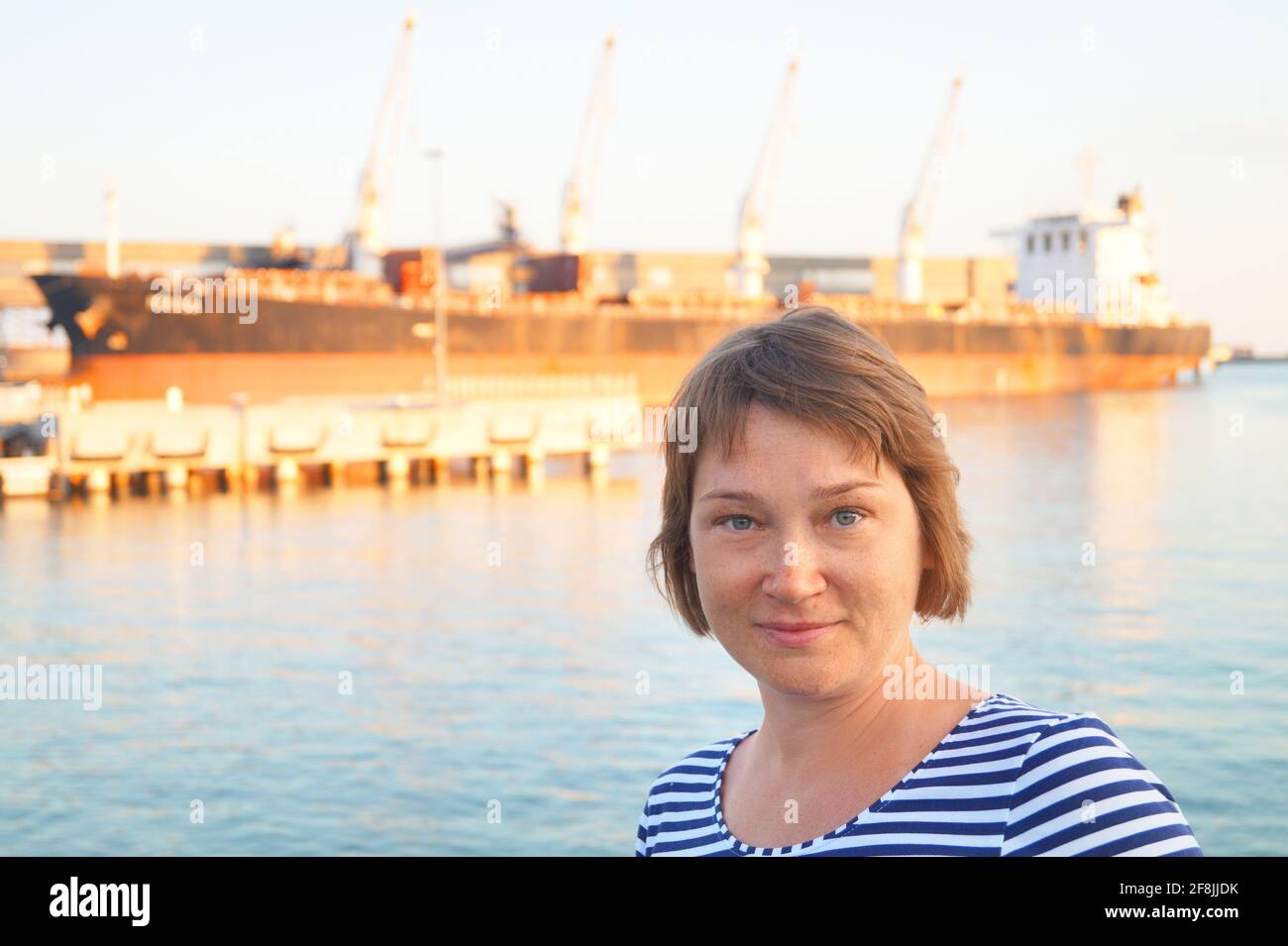 A woman stands in front of a loading trawler Stock Photo