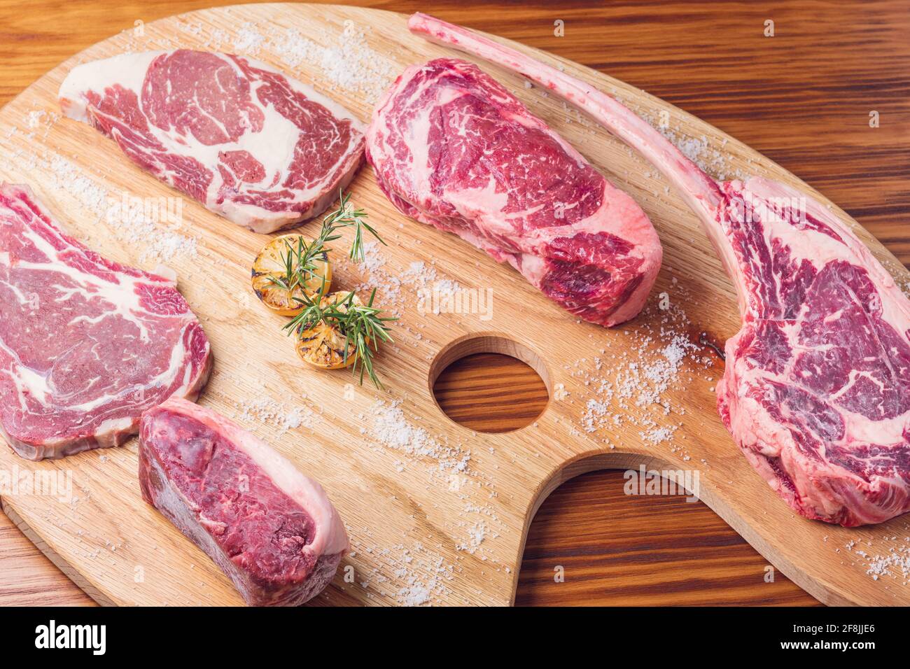 https://c8.alamy.com/comp/2F8JJE6/cuts-of-raw-steak-premium-on-rustic-wooden-table-fresh-and-raw-meat-2F8JJE6.jpg