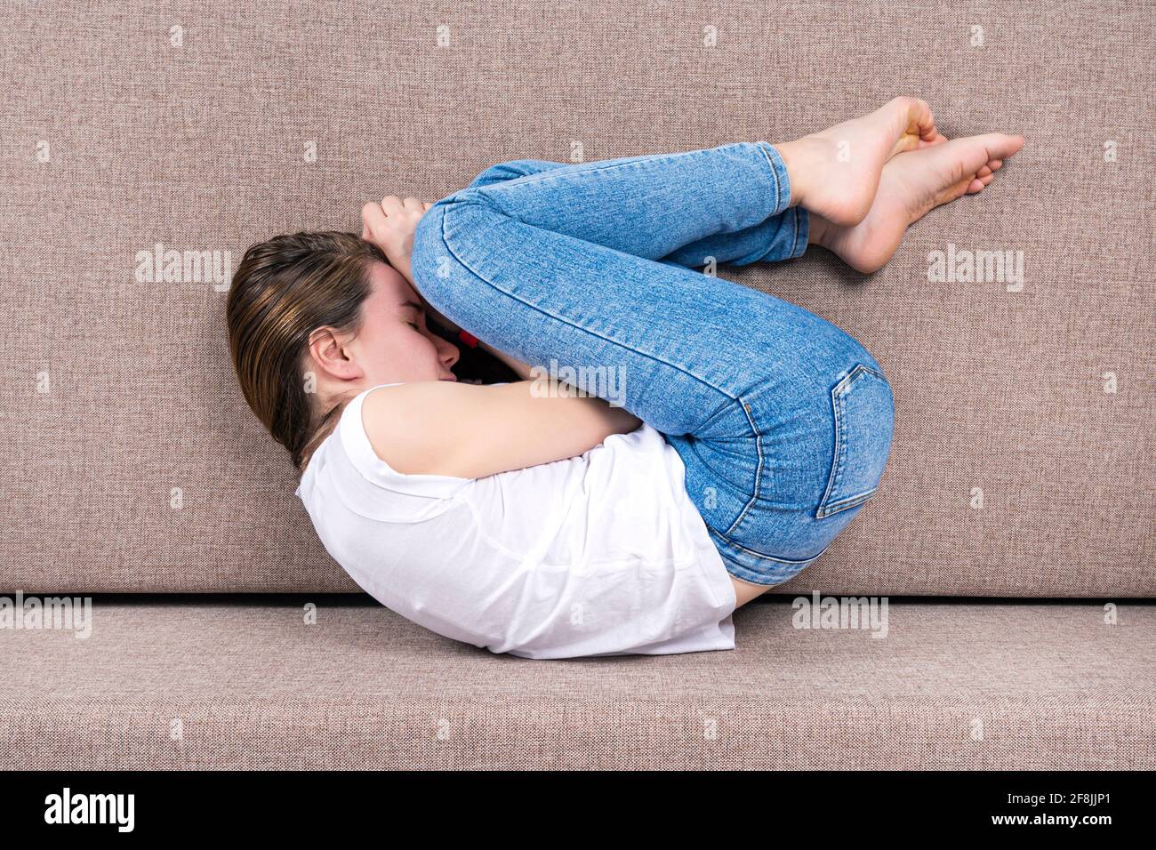 Young woman lies in Fetal or Embryo Posture. Top view Stock Photo