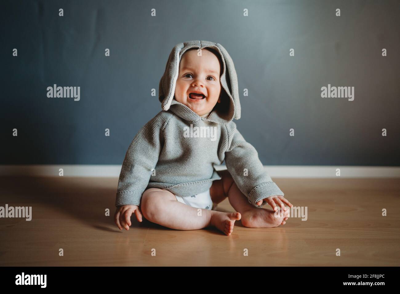Cute smiling baby boy wearing a bunny jumper with ears for Easter Stock Photo