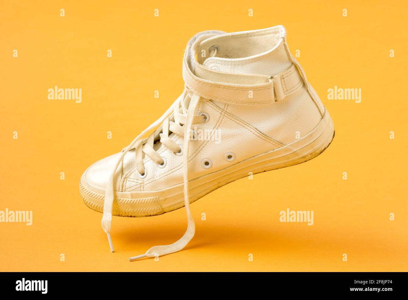 White leather shoe falling on the yellow background Stock Photo Alamy
