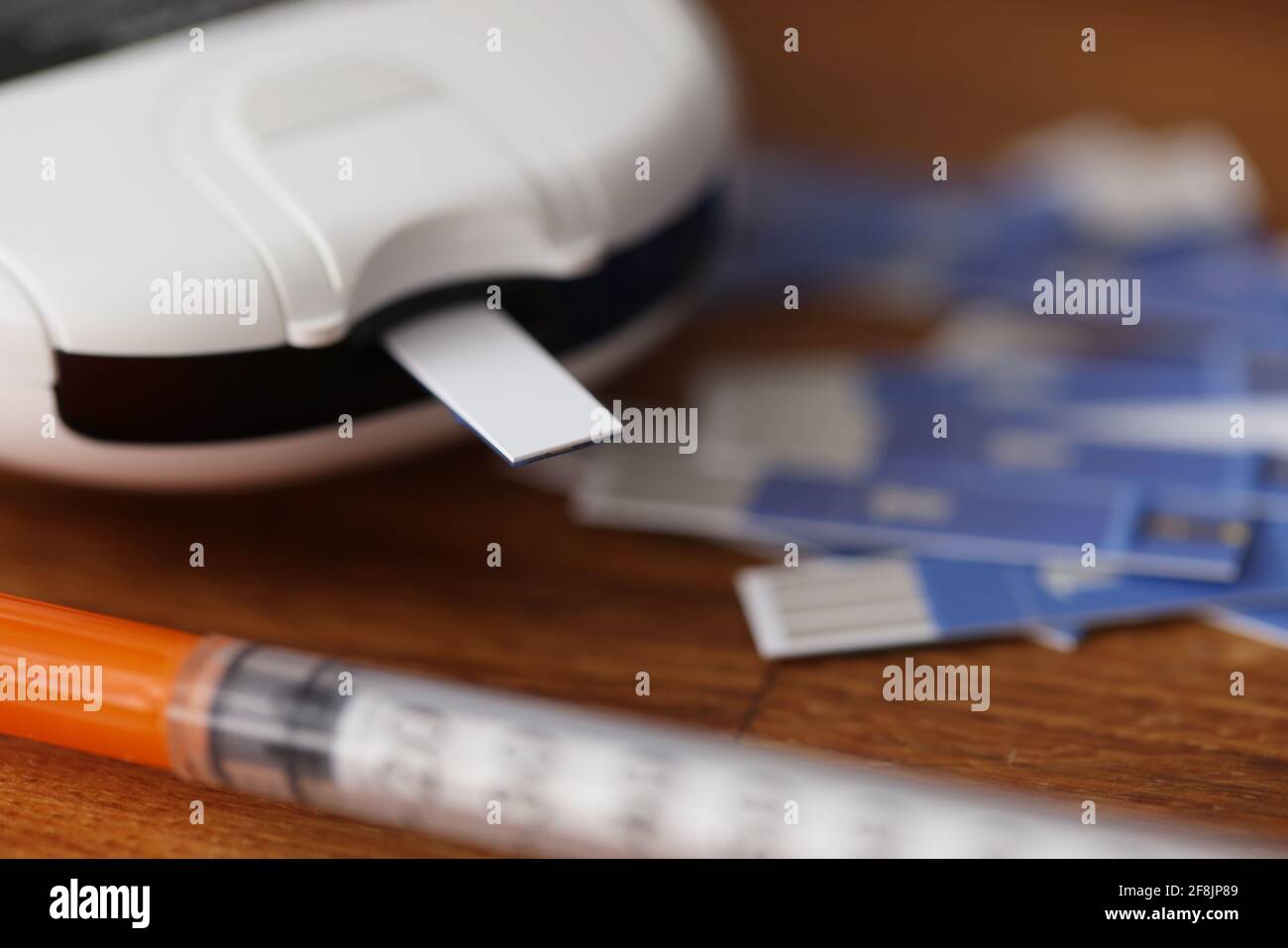 Glucometer with test strips and syringe with insulin lying on table closeup Stock Photo