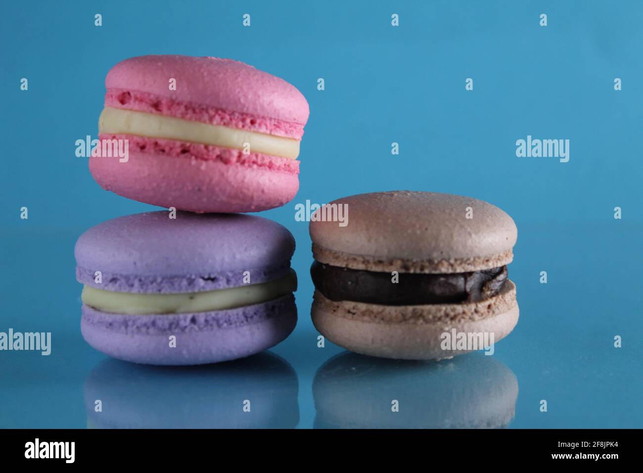 three macaroons lie triangle on a blue background with a place for text and copyspace. Stock Photo