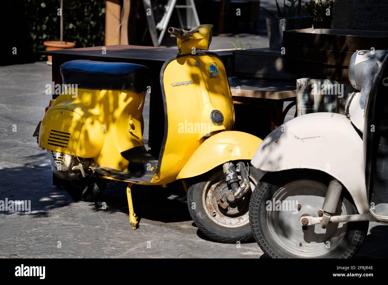 An vintage bright yellow iconic Vespa motor scooter parked up on a street in Rhodes City Old Town on the island of Rhodes, Greece Stock Photo