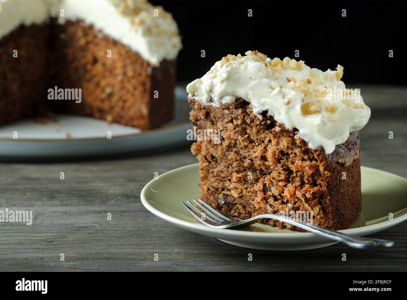 A home baked gluten free carrot and walnut cake. This moist cake has an indulgent cream cheese topping and was made with gluten free ingredients Stock Photo
