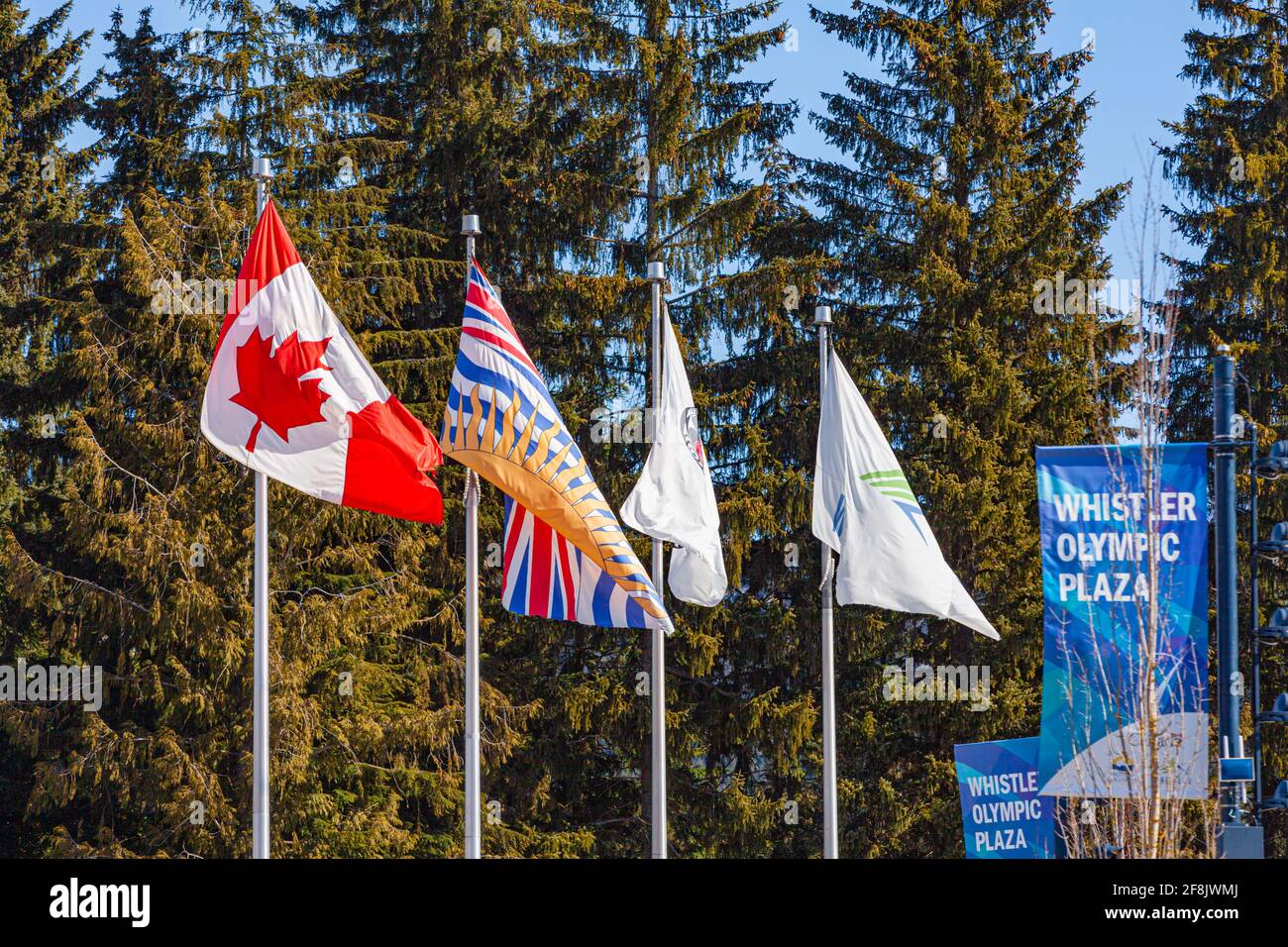 Canadian, British Columbian, First Nations, and the Whistler village flags blowing in the wind in Whistler Village British Columbia Canada Stock Photo