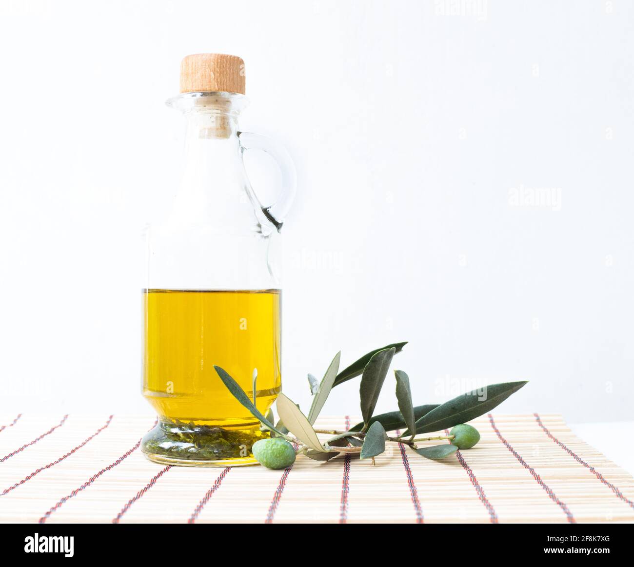 Glass bottle of olive oil and some olives with leaves isolated on a ...