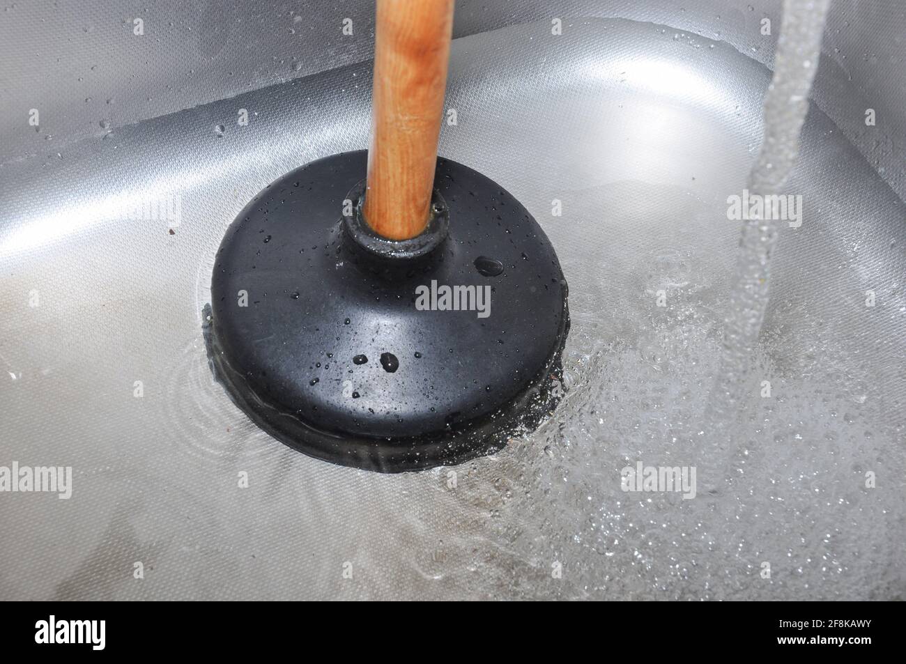 Plunger and clogged kitchen sink. Pipe cleaning concept. Sanitary engineering work. Stock Photo