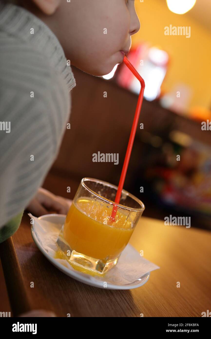 Toddler drinking fresh orange juice in the cafe Stock Photo Alamy