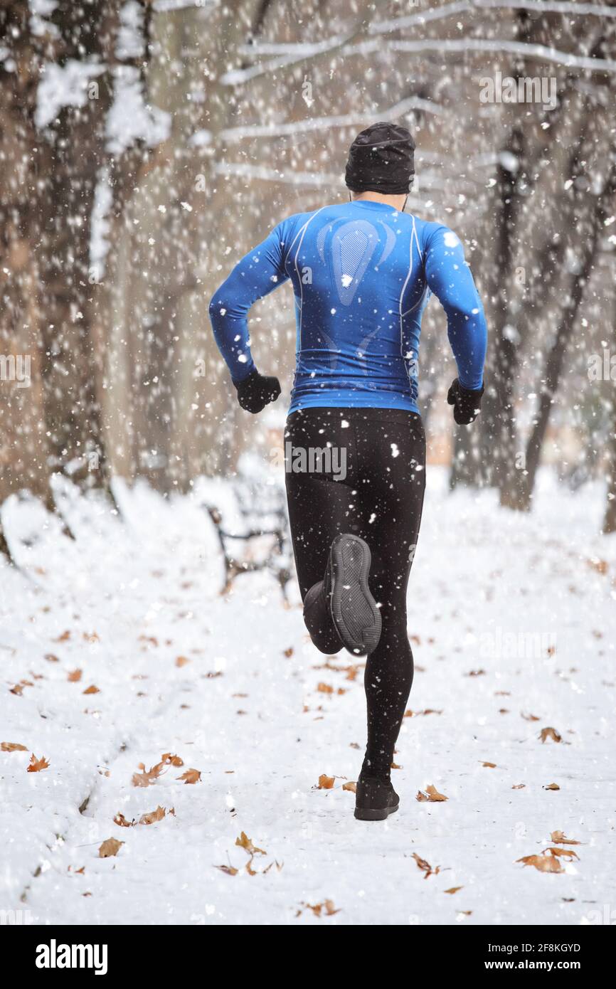 Full length rear shot of a man in winter sports outfit running on snow in a  park Stock Photo - Alamy