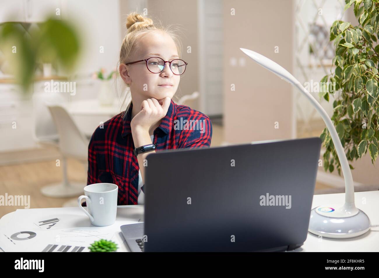 Blonde girl with glasses work on a laptop. Home-school concept Stock Photo