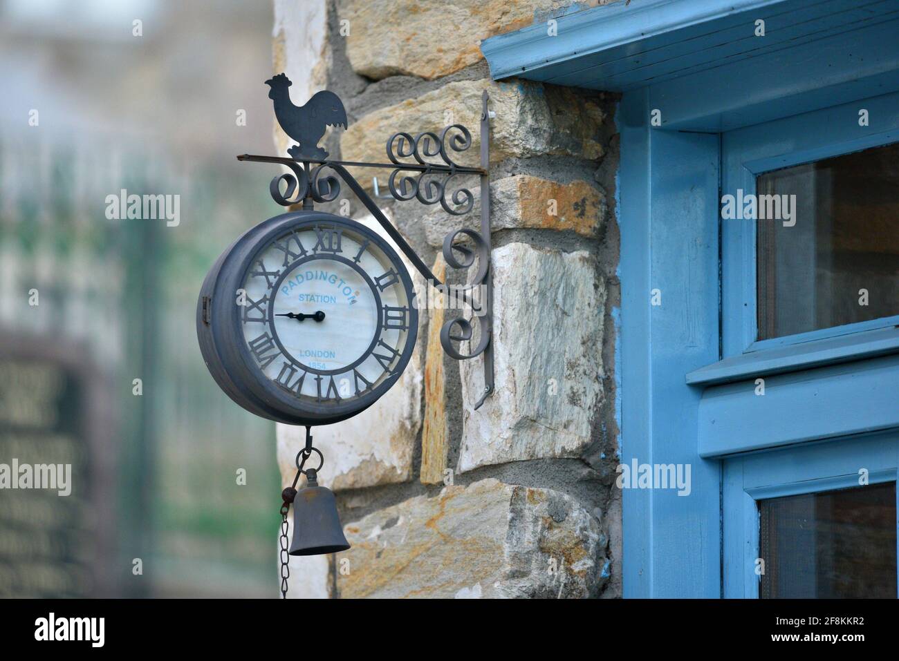 Vintage Paddington Station tin clock with a hanging bell on a stone