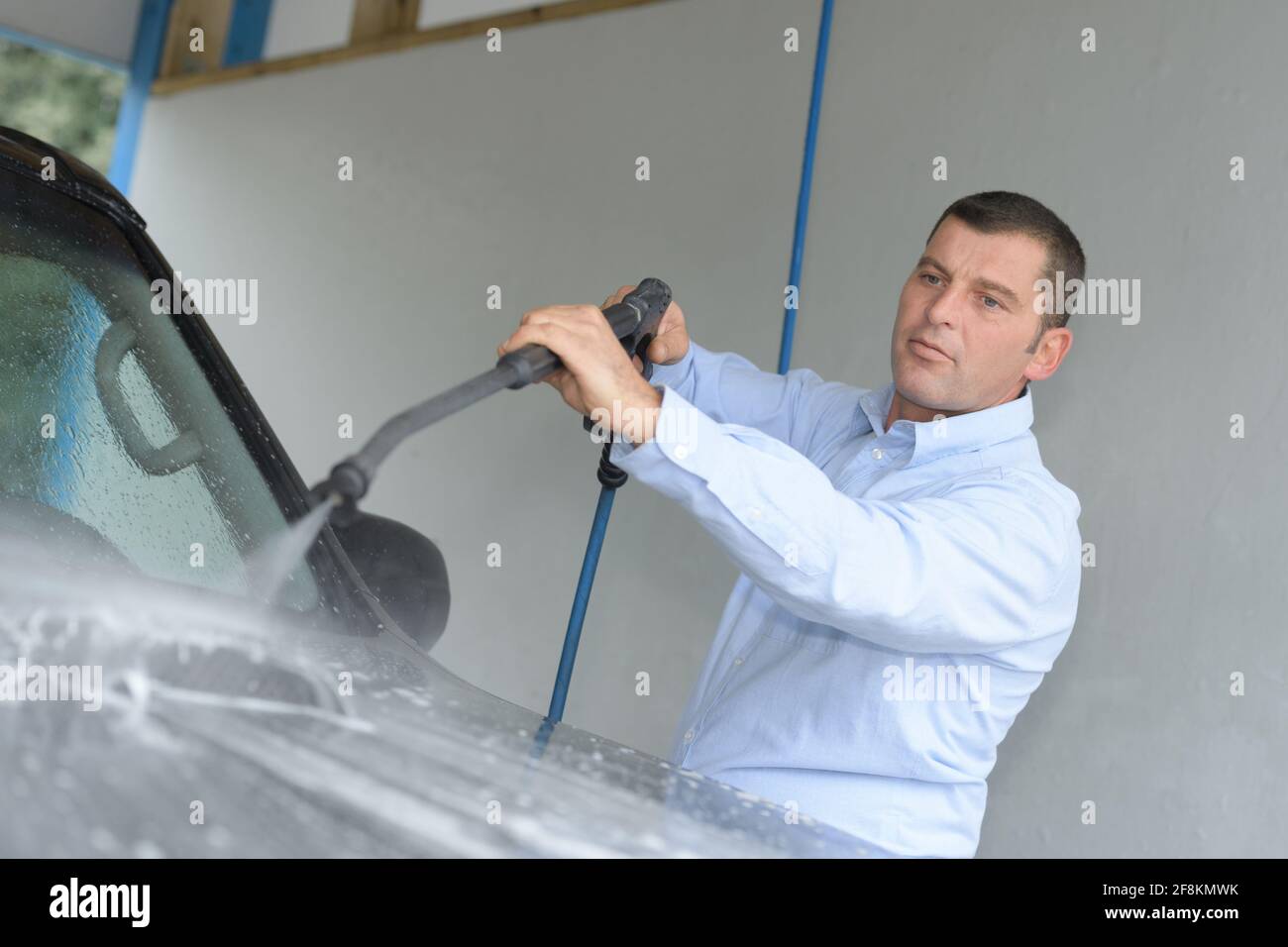 man washing a car with pressured water Stock Photo