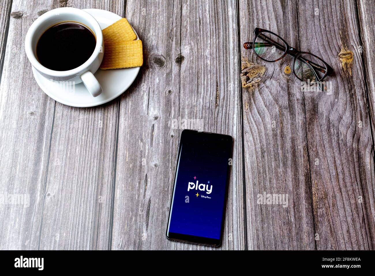 A Mobile phone or cell phone laid on a wooden table showing the Play disney Parks app on screen Stock Photo