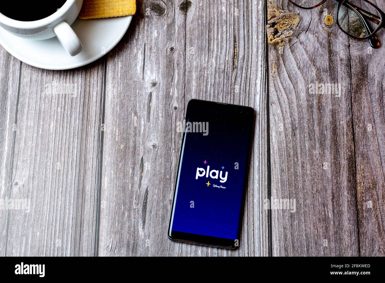 A Mobile phone or cell phone laid on a wooden table showing the Play disney Parks app on screen Stock Photo