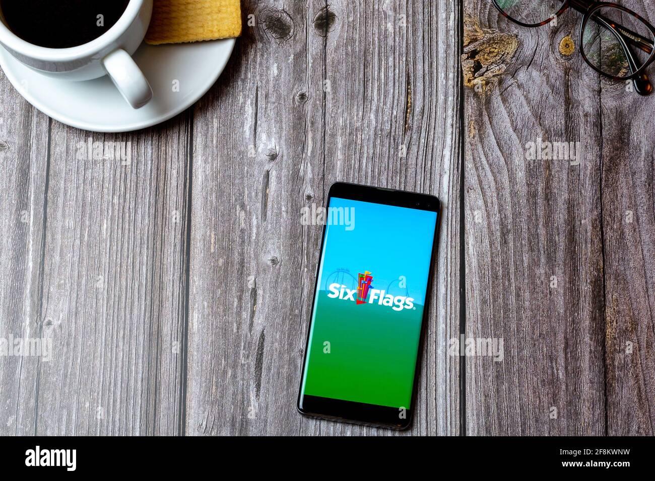 A Mobile phone or cell phone laid on a wooden table showing the Six Flags app on screen Stock Photo