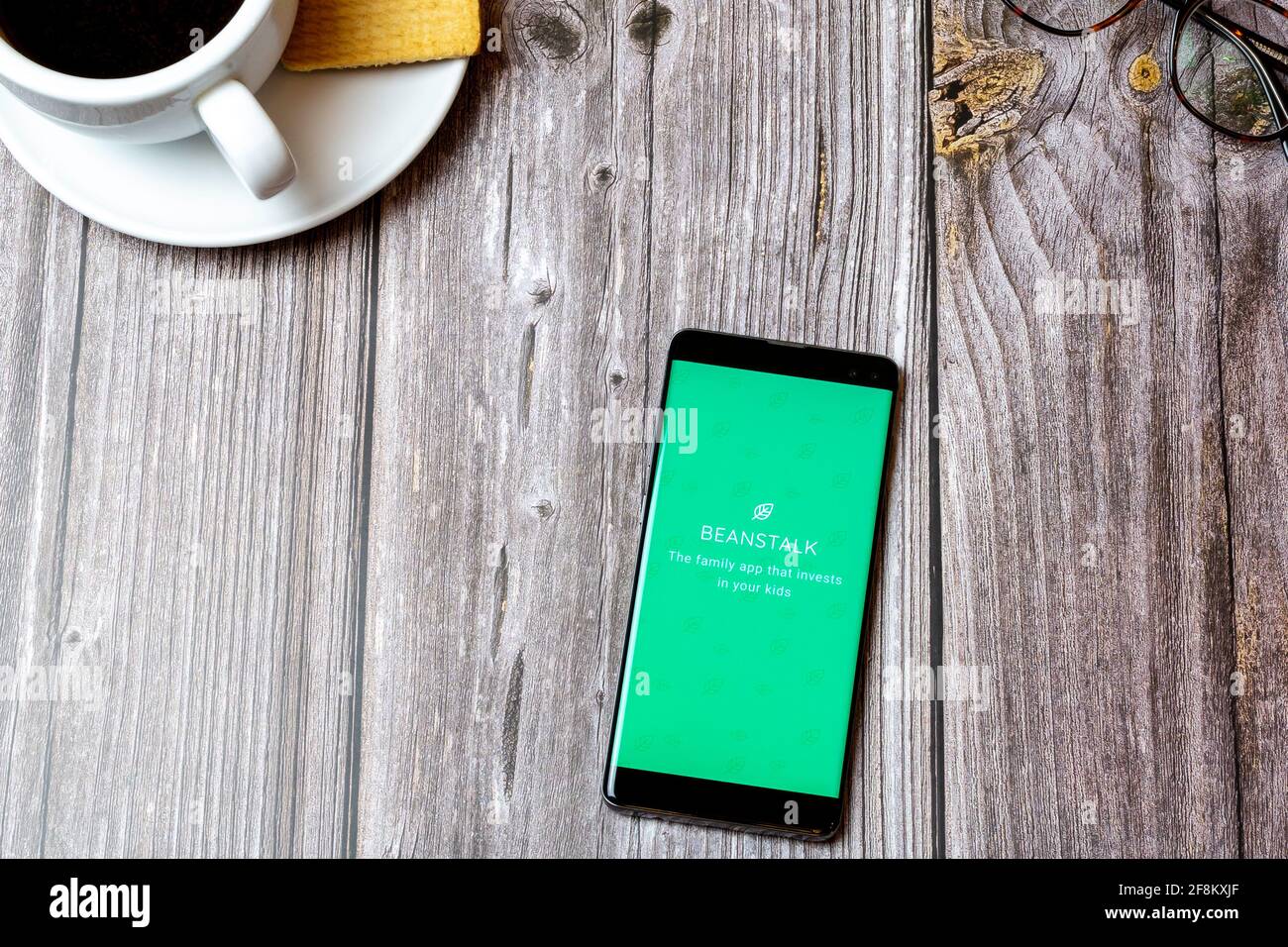 A Mobile phone or cell phone laid on a wooden table showing the Beanstalk app on screen Stock Photo