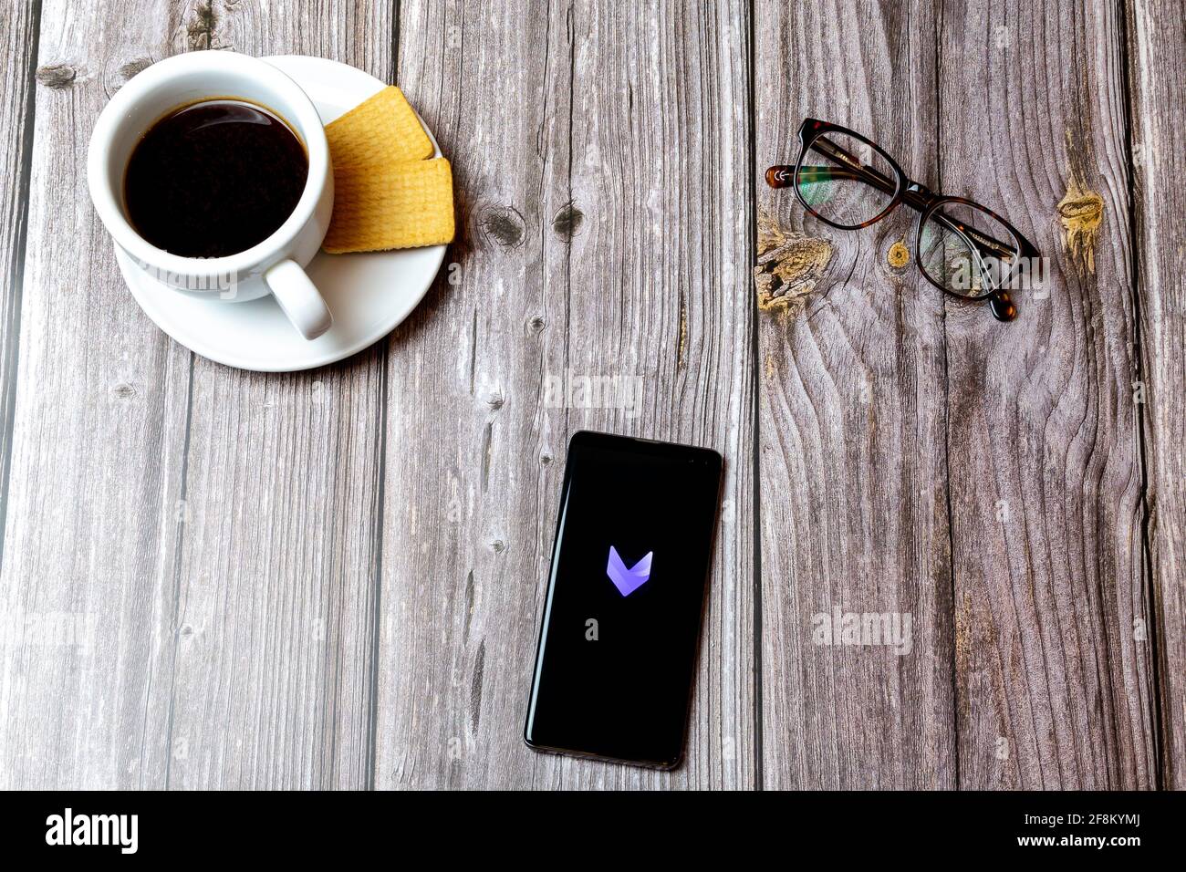 A Mobile phone or cell phone laid on a wooden table showing the Vivacut  editing app on screen Stock Photo - Alamy