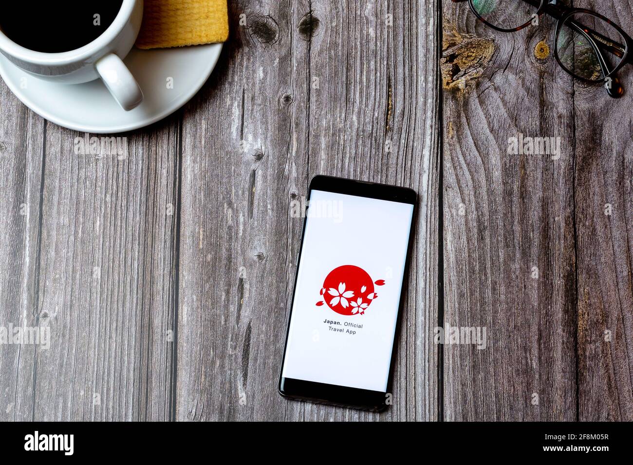 A Mobile phone or cell phone laid on a wooden table showing the japan official travel app on screen Stock Photo