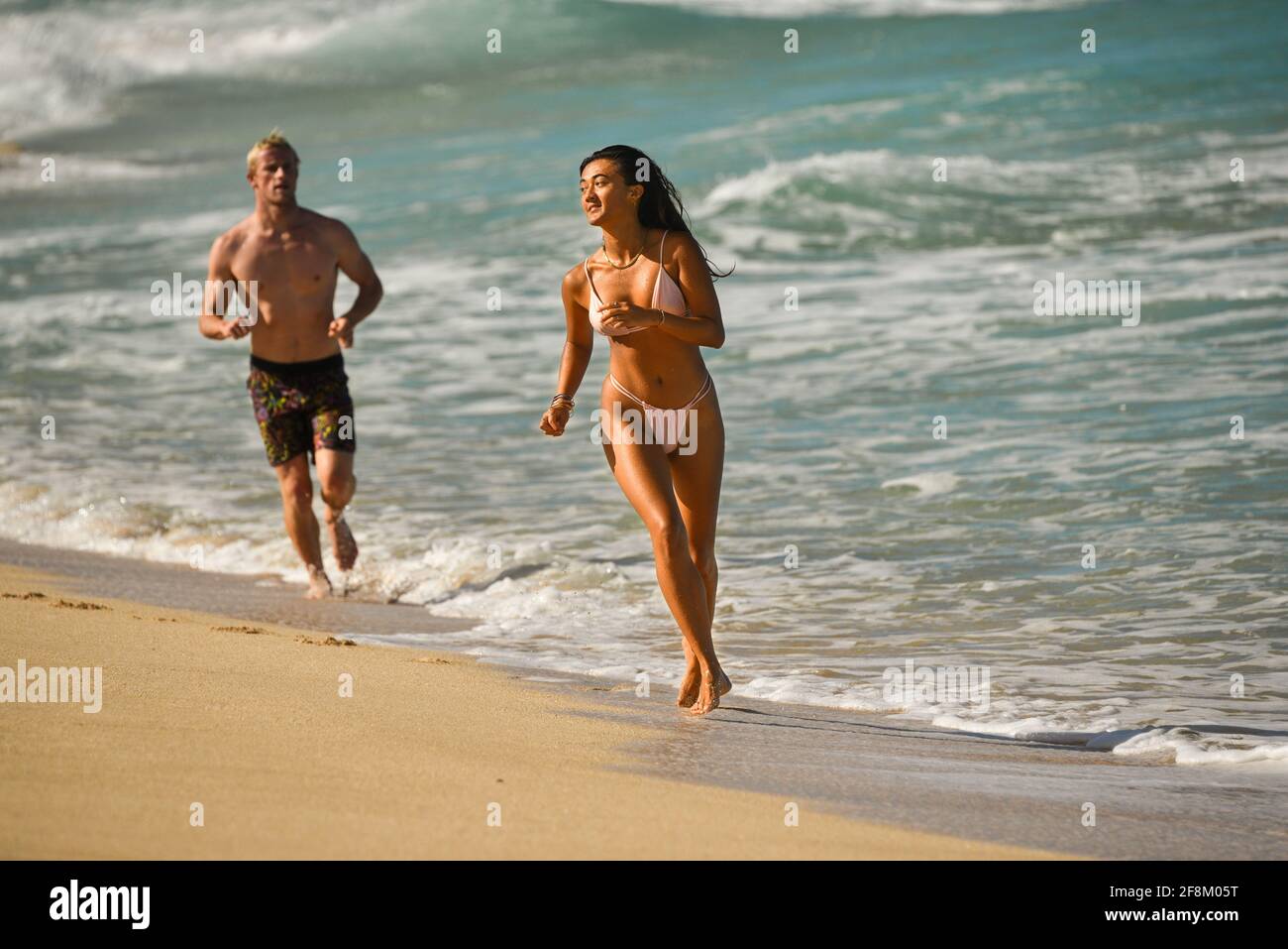 Hawaiian woman in sexy thong bikini and boyfriend, running and chasing each  other, swimming in tropical warm waters, North Shore, Oahu, Hawaii, USA  Stock Photo - Alamy