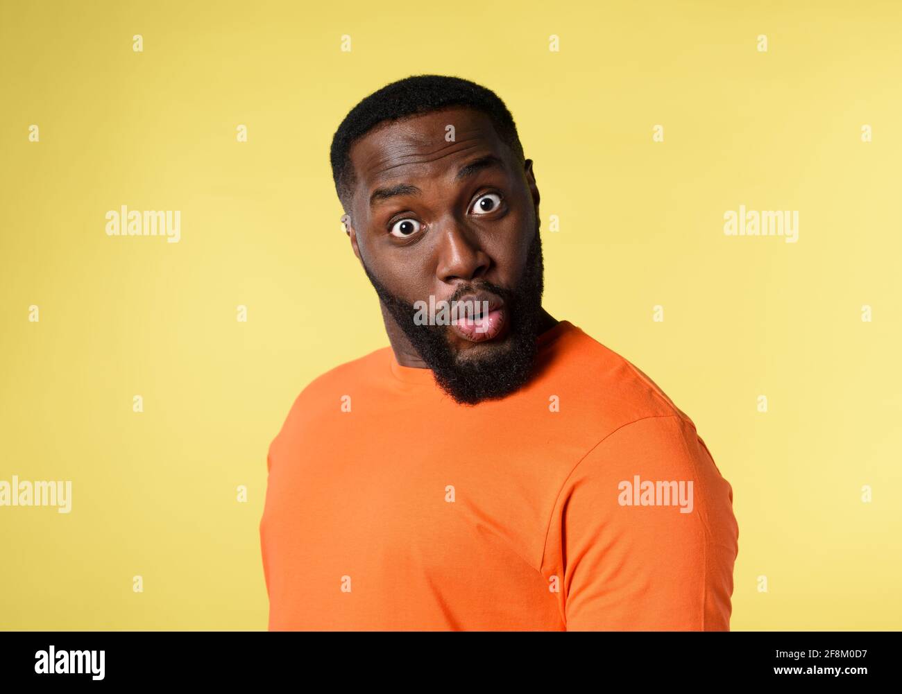 Black man with surprised and amazed expression. yellow background Stock