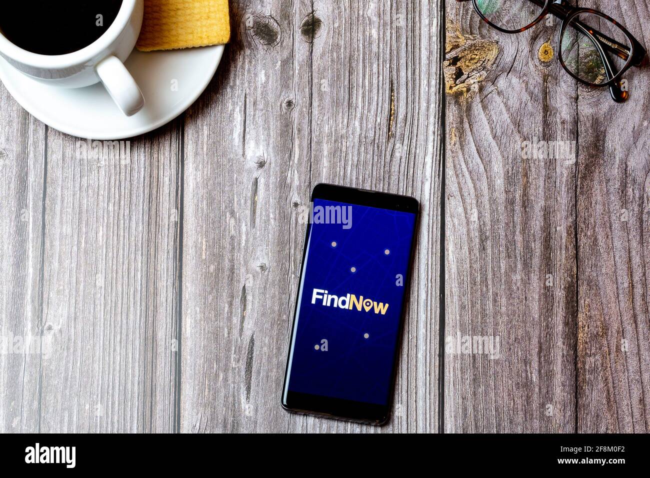 A Mobile phone or cell phone laid on a wooden table showing the Findnow ...