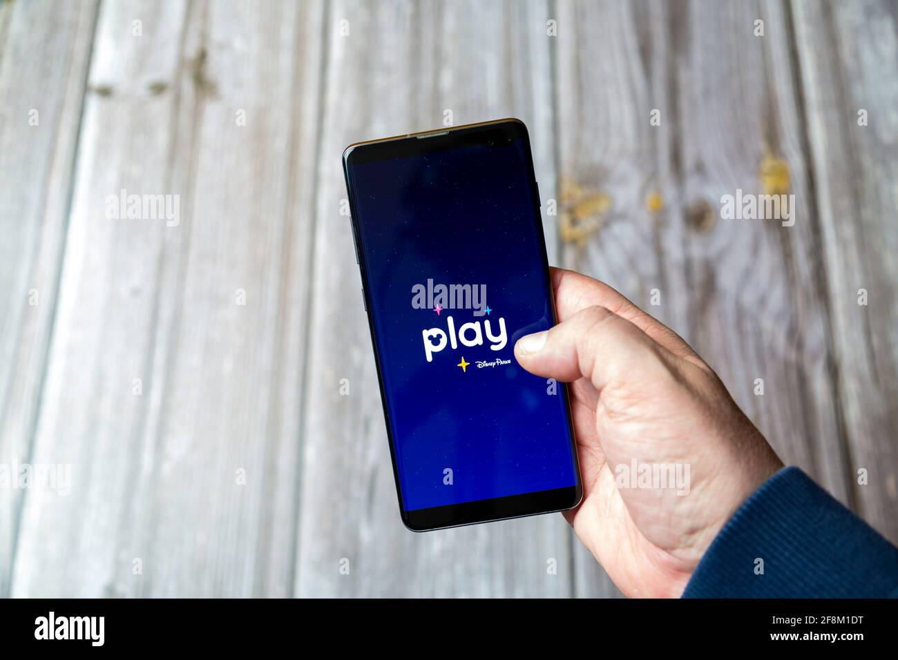 A Mobile phone or Cell phone being held in a hand showing the Play disney parks app on screen Stock Photo