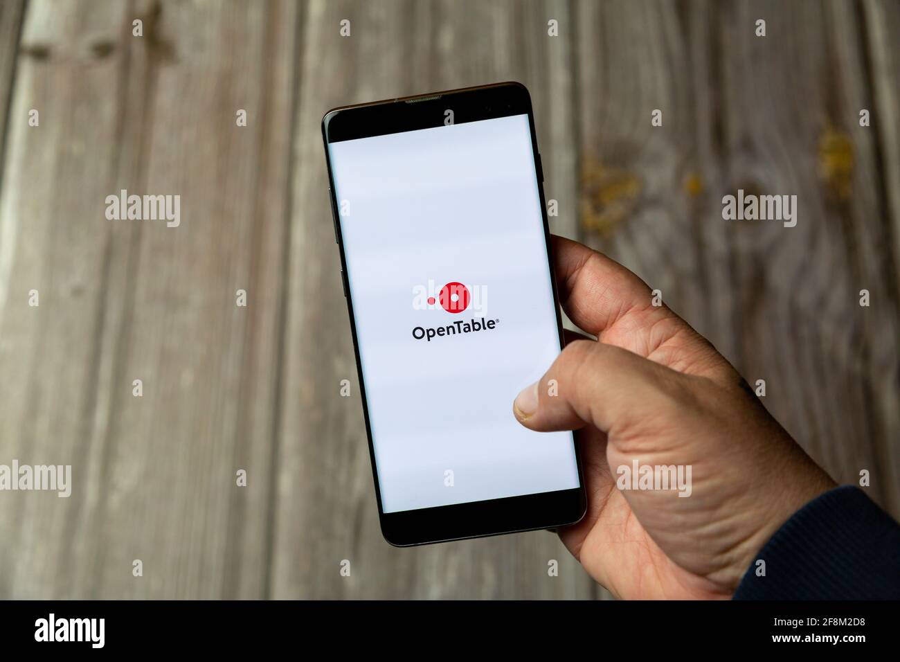 A Mobile phone or Cell phone being held in a hand showing the open table app on screen Stock Photo