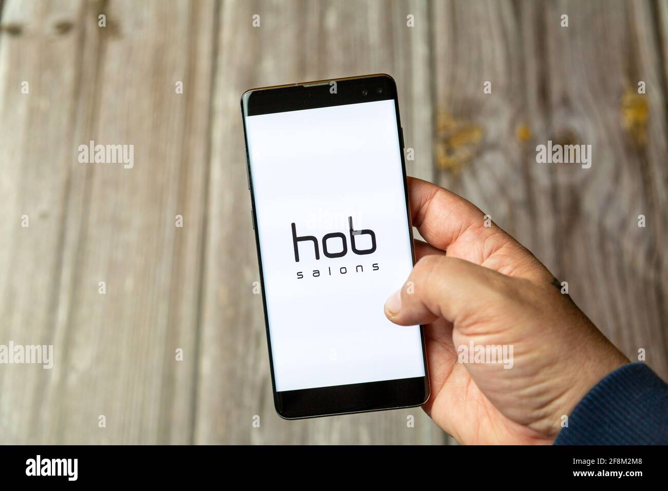 A Mobile phone or Cell phone being held in a hand showing the hob salons app on screen Stock Photo