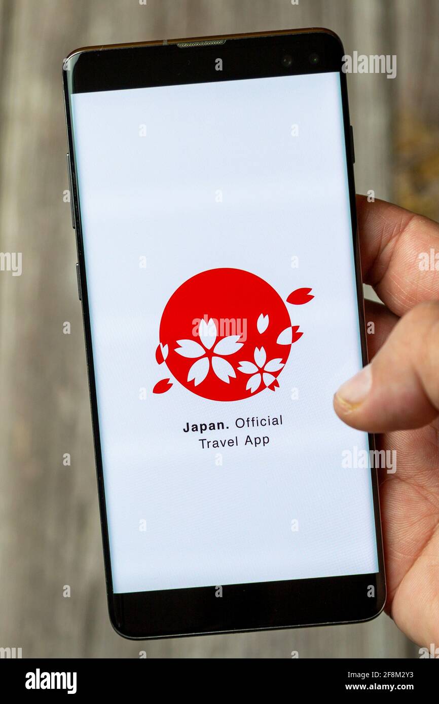 A Mobile phone or Cell phone being held in a hand showing the japan official travel app on screen Stock Photo