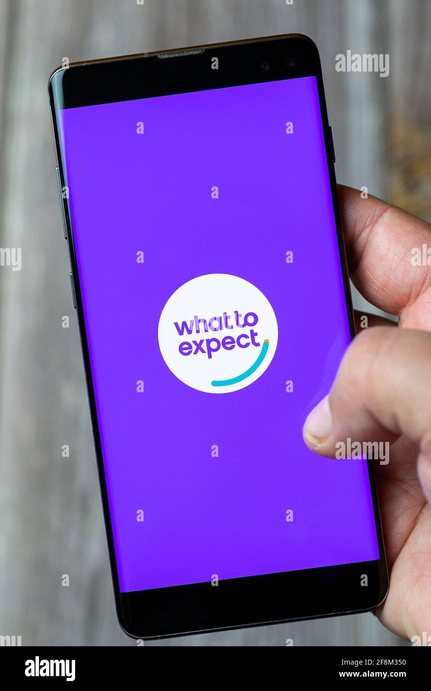 A Mobile phone or Cell phone being held in a hand showing the what to expect pregnancy app on screen Stock Photo