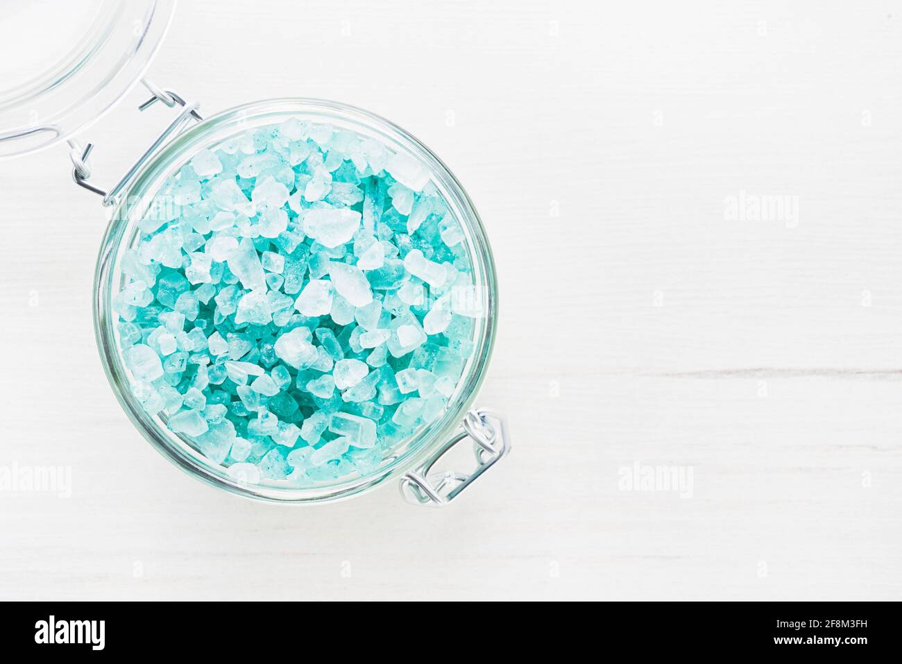 Blue aroma bath salt in a glass jar on white wooden background. Spa, skincare concept. Top view, copy space. Selective focus Stock Photo