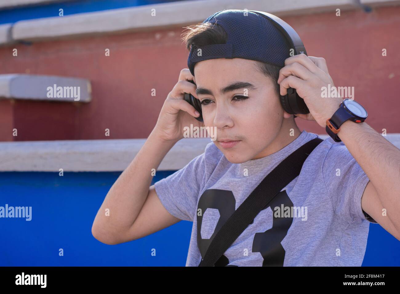12 year old preteen, putting his black headphones on top of his hat backwards. Stock Photo