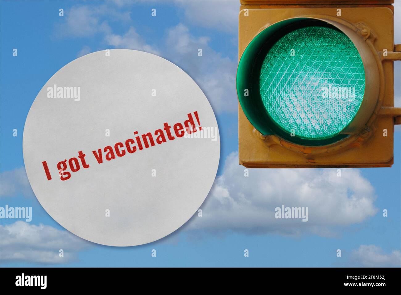 photo collage of a I got vaccinated sticker and a green traffic light against a sky, representing activities opening being allowed as more people get Stock Photo