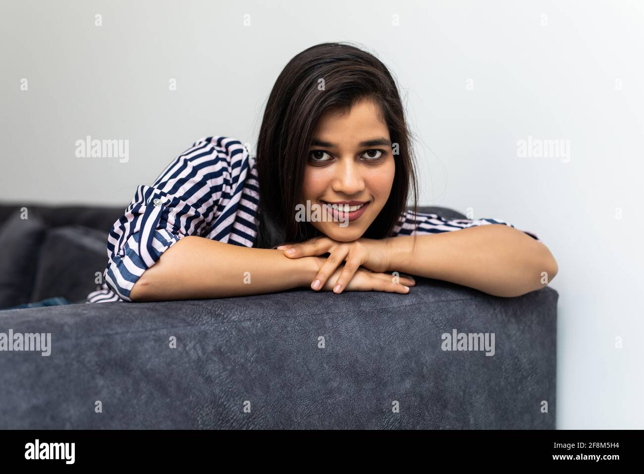 Happy young indian woman lying on couch and relaxing at home Stock ...