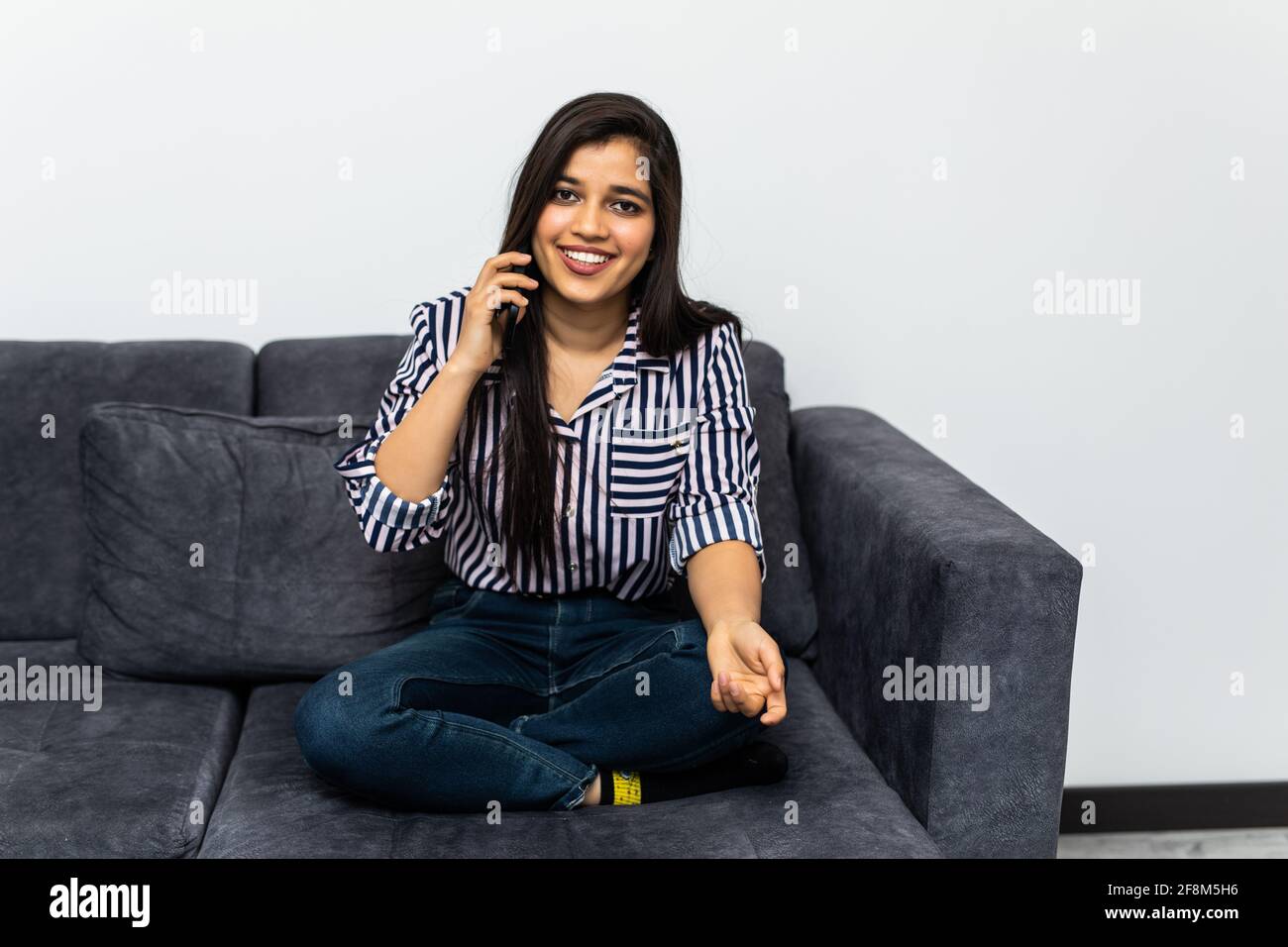 Happy indian woman talking cell phone in loft apartment Stock Photo - Alamy
