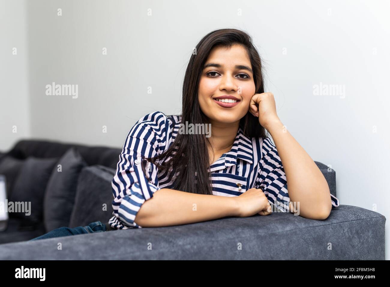 Happy young indian woman lying on couch and relaxing at home Stock ...