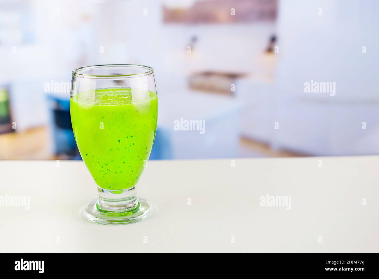 Glass of juice with cucumber and parsley on white table, Detox cocktail of raw fruits and vegetables and lettuce and parsley, the background is out of Stock Photo
