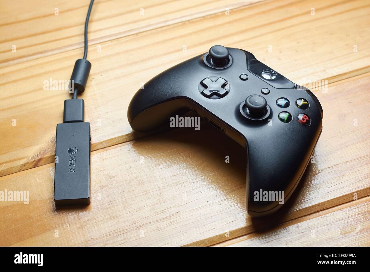 APRIL 12, 2021 - BUENOS AIRES, ARGENTINA: Top view of black Xbox One game controller and receiver for PC on wooden table. Stock Photo