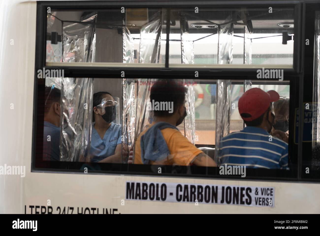 A health worker in Cebu City, Philippines wearing a face mask and shield whilst using public transport, The wearing of shields and masks is a requirme Stock Photo