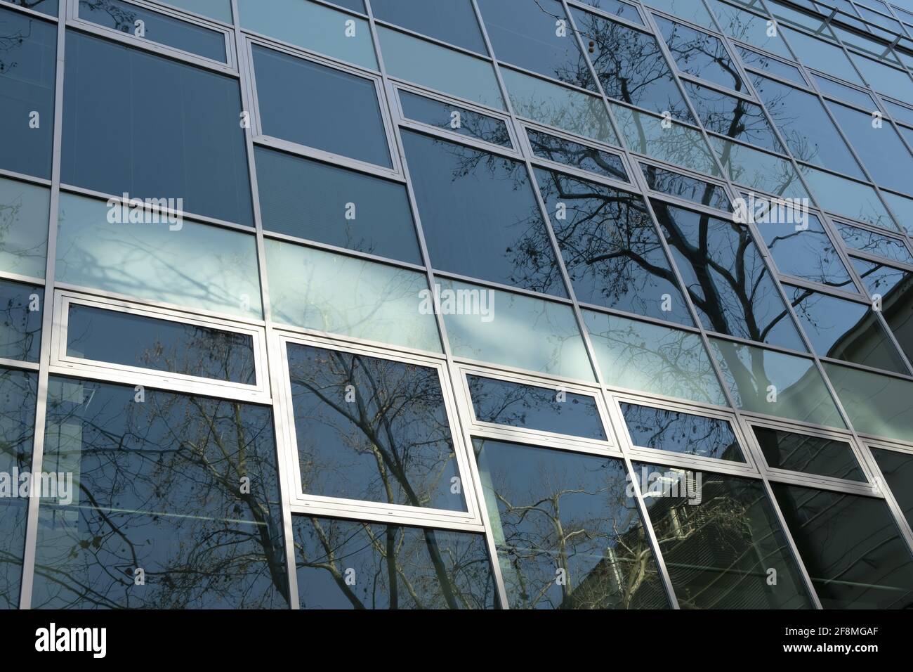 Exterior Windows Of A Modern Commercial Office Building. low angle view of a glass modern facade with reflections Stock Photo